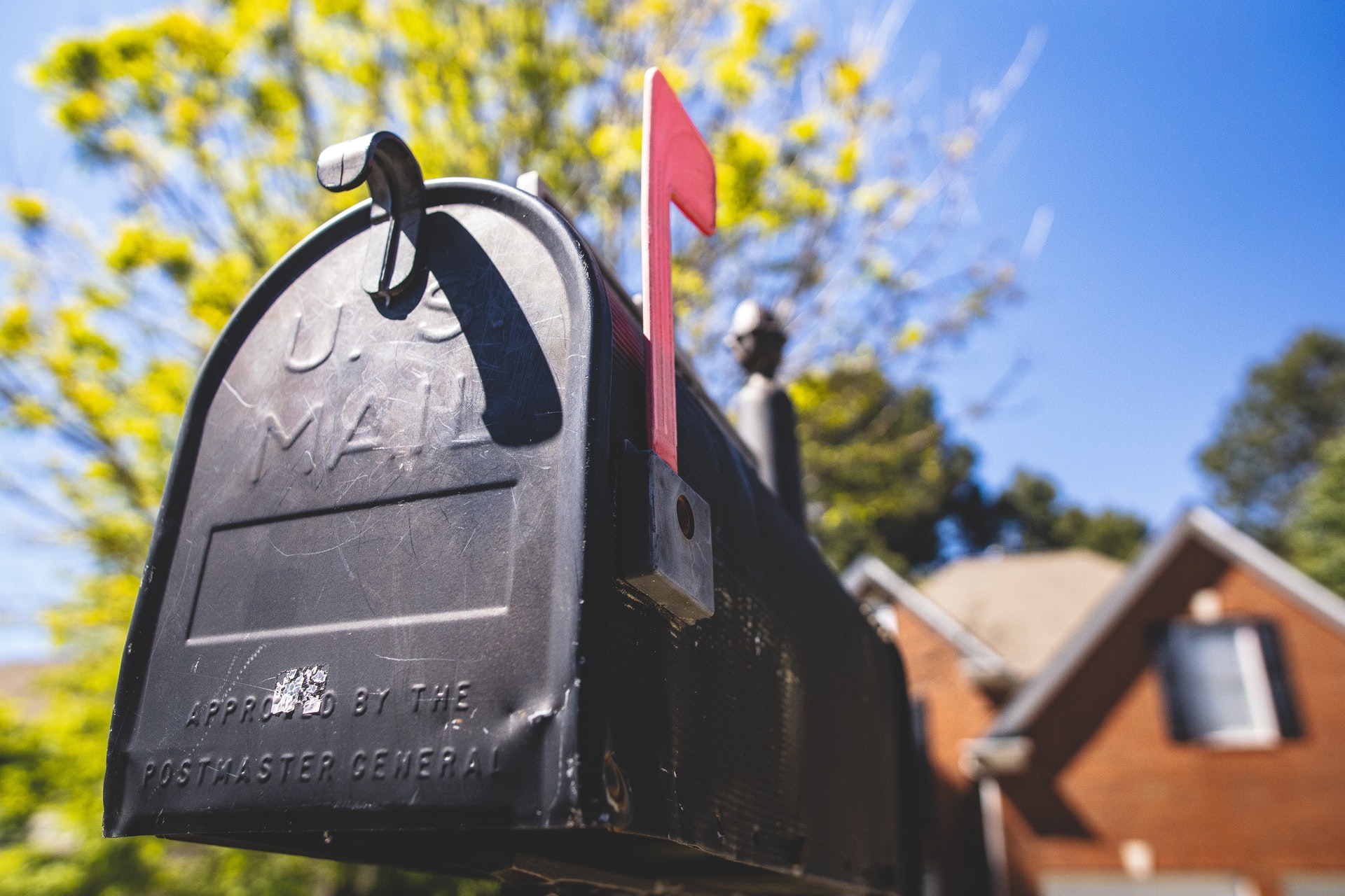 Close up of a mailbox with a sunny day and a tree and house in the background